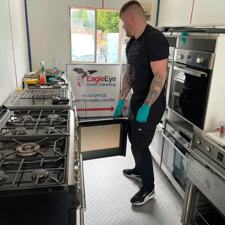A trainee holding a dismantled oven door in the training workshop